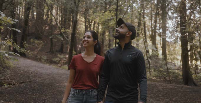 Neha Bhatia and husband walking holding hands on forest trail