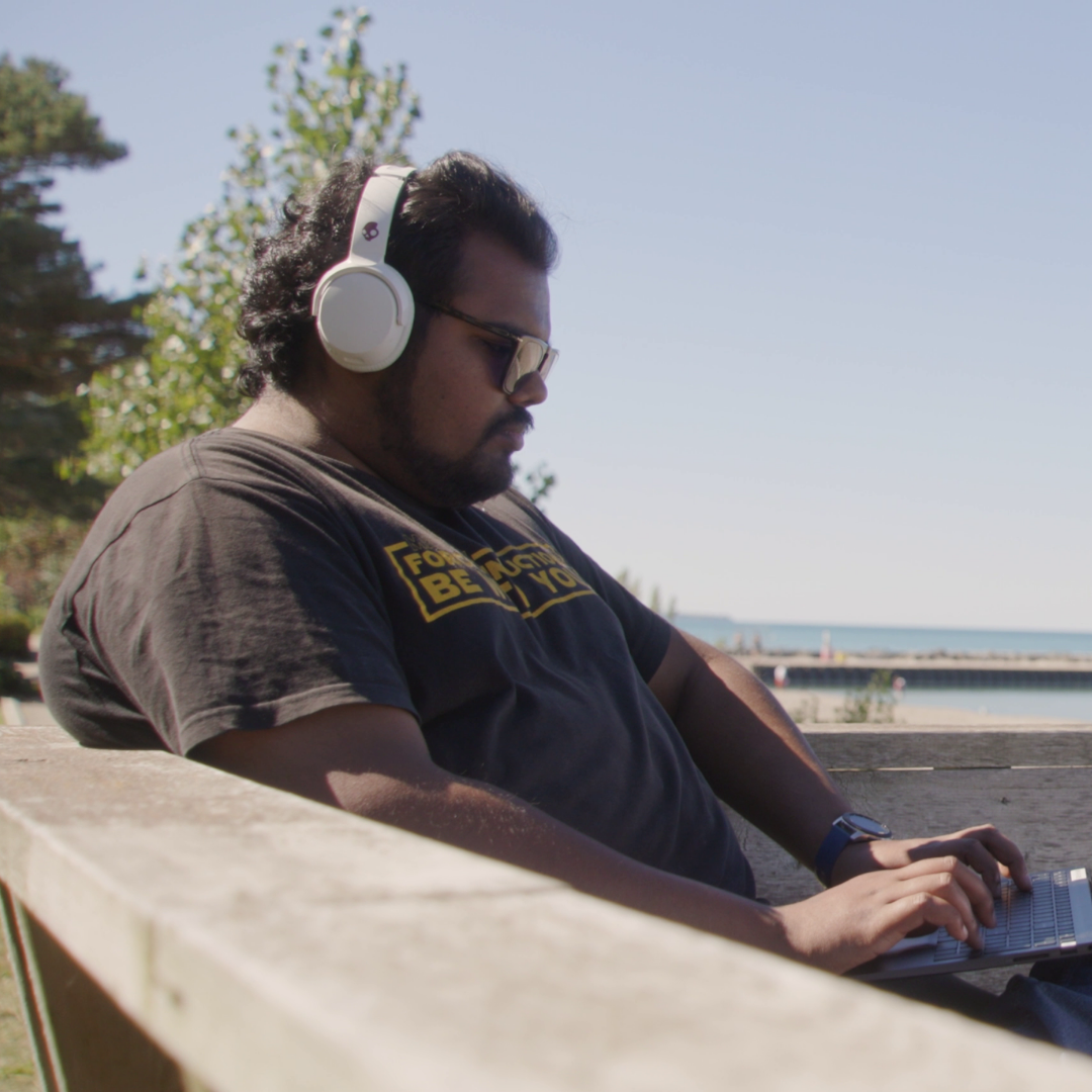 Man sitting on a bench by the water on his labtop